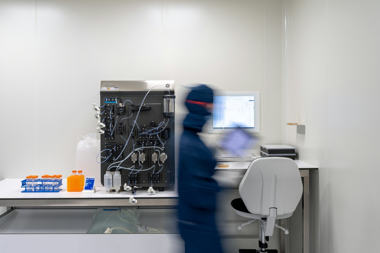 Scientist in blue suit operating complex laboratory equipment.